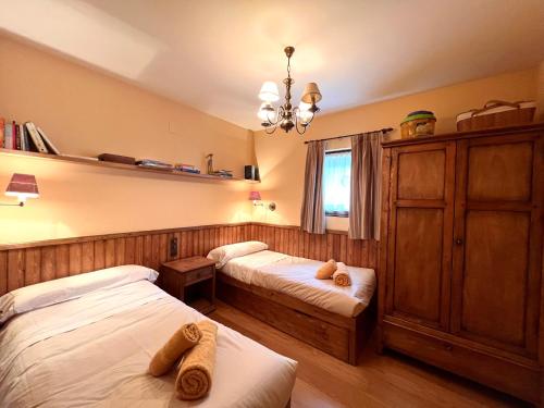 a bedroom with two beds and a chandelier at Apartament de la Vall Ferrera in Areu