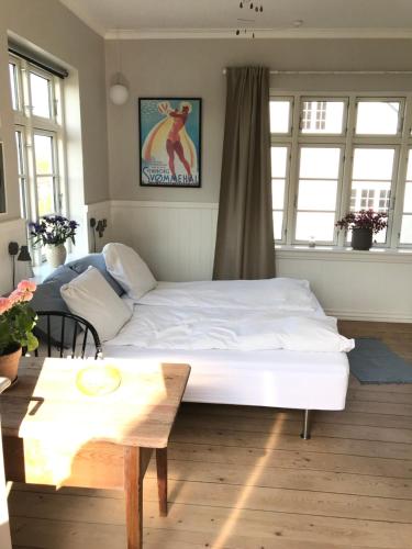 a bedroom with a large white bed and a table at BnB Thuroe in Svendborg