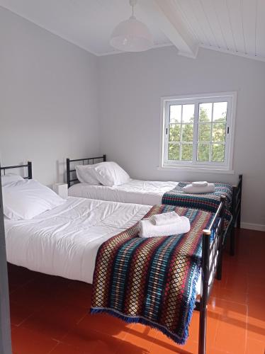 two beds in a white room with a window at Villa Visconde in Nordeste