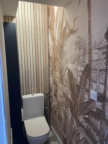 La salle de bains est pourvue de toilettes et de papier peint tropical. dans l'établissement Superbe appartement rénové et au bord de la mer, à Palavas-les-Flots