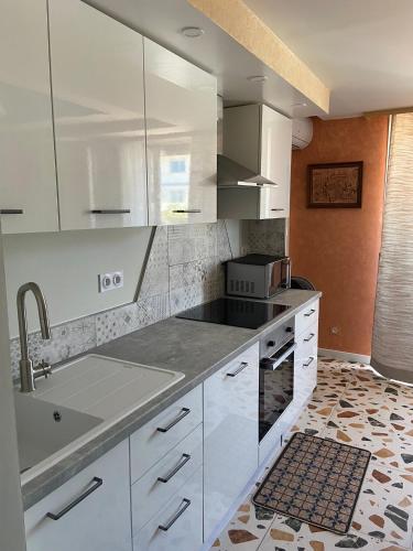 une cuisine avec des armoires blanches et un évier dans l'établissement Superbe appartement rénové et au bord de la mer, à Palavas-les-Flots