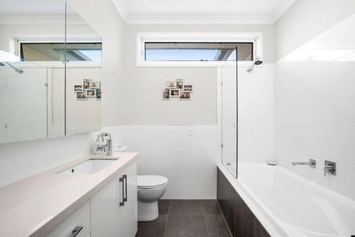 a white bathroom with a toilet and a sink at Explore Frankston South from this lovely home in Frankston