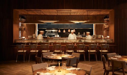 a restaurant with tables and a chef in the kitchen at Nobu Hotel Marrakech in Marrakech