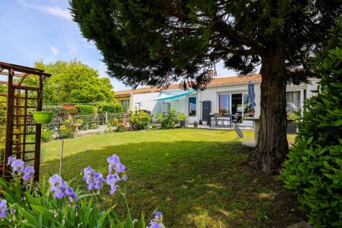 ein Haus mit einem Hof mit einem Baum und lila Blumen in der Unterkunft "Logis Debussy"- Saintes in Saintes