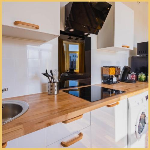 a kitchen with white cabinets and a wooden counter top at « Le Terminus » à 250m de la gare in Tourcoing