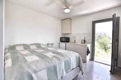a white bedroom with a bed and a kitchen at Little house in the olive grove in Melissátika