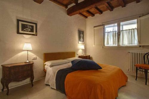 a bedroom with a bed with an orange blanket and a window at Il Tulipano Apartment With Patio in Florence