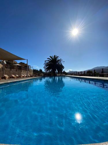 a large blue swimming pool with the sun in the sky at Cabañas & Spa Qamawi in Pan de Azúcar