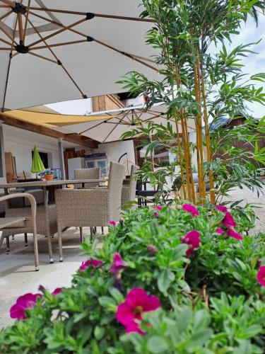 a patio with tables and chairs and pink flowers at Zwei Hirsche in Seefeld in Tirol