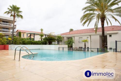 - une piscine dans la cour d'un immeuble avec des palmiers dans l'établissement Air conditioning Studio with pool St Laurent du Var, à Saint-Laurent-du-Var