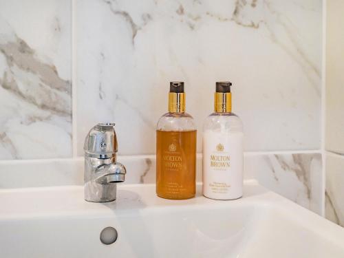 two bottles of alcohol sitting on a bathroom sink at Pittendrigh Cottage in Briston