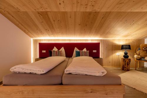 a bedroom with two beds with a red headboard at Hotel Martellerhof in Martello