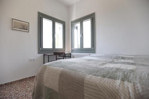 - une chambre blanche avec un lit et 2 fenêtres dans l'établissement Admonis - Home in the olive grove, à Melissátika