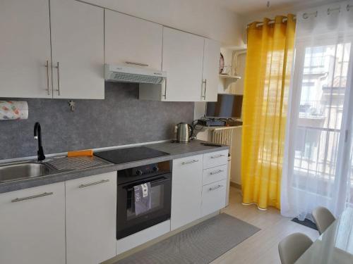 une cuisine avec des armoires blanches et un évier dans l'établissement Cozy Lemon Menton, à Menton