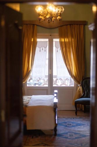 a bedroom with a bed and a window and a chandelier at Bujtina Sidheri in Korçë