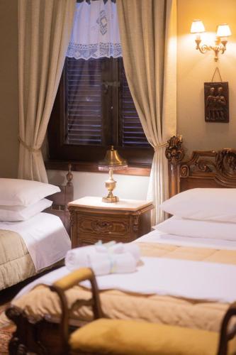 a bedroom with two beds and a chair and a window at Bujtina Sidheri in Korçë