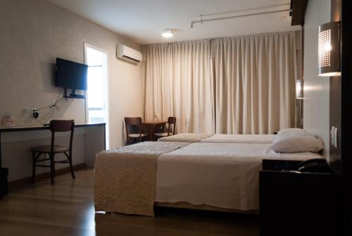 um quarto de hotel com uma cama, uma mesa e cadeiras em Master Express Moinhos de Vento em Porto Alegre