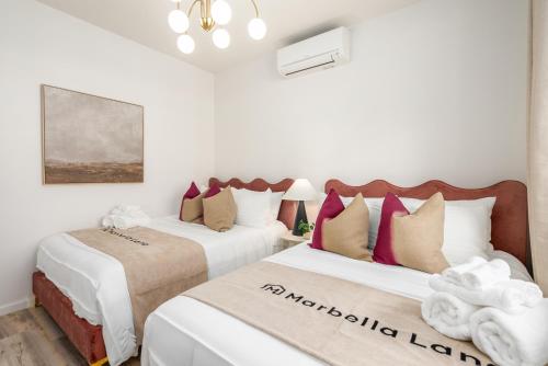 two beds in a room with white and red pillows at #ML - Aloha Hoʻonani 3BR Home - MT & Ocean Views! in Waianae