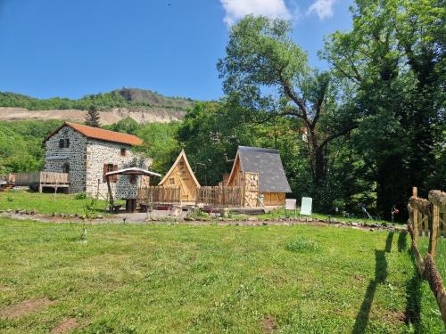 une cabane en rondins avec une terrasse et une maison dans l'établissement Les cabanes féeriques du Cheix, à Saint-Diéry
