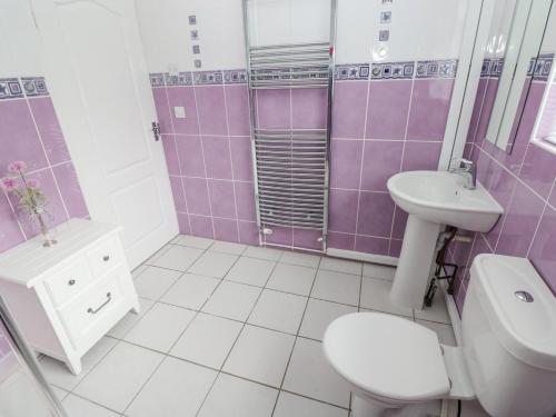 サンダースフットにあるAshdown Houseの紫と白のバスルーム(トイレ、洗面台付)