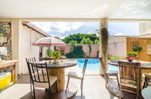 a patio with a table and chairs and a swimming pool at Pousada Bem te vi in Bragança Paulista