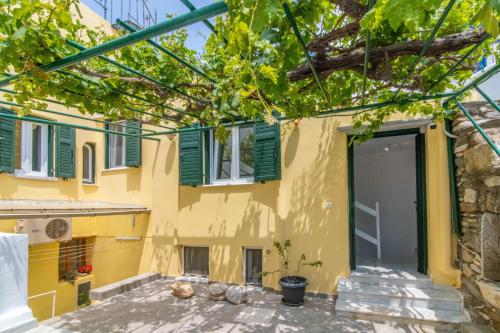 a building with green shuttered windows and a door at Chora 5 - Central Rooms by TinosHost in Tinos Town