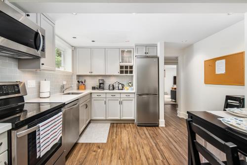 a kitchen with white cabinets and a stainless steel refrigerator at Gorgeous 4-Bedroom Garden Level Suite at Vancouver West in Vancouver