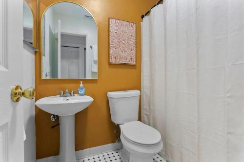 a bathroom with a toilet and a sink and a mirror at Boho Inspired Apt in the heart of Tampa Bay! in Tampa