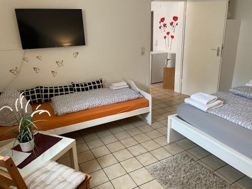 a bedroom with two beds and a tv on the wall at Gästehaus Jeurissen ca 5 Autominuten von Europa-Park Rust oder Rulantica in Kappel-Grafenhausen