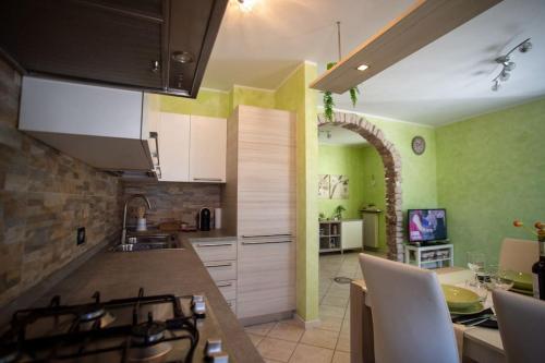 a kitchen with green walls and a dining room at *[Stella Alpina]*accogliente casa, giardini, wi-fi in Borgo Lares