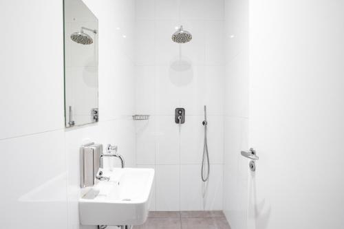 a white bathroom with a sink and a shower at Sophie's Hostel in Prague