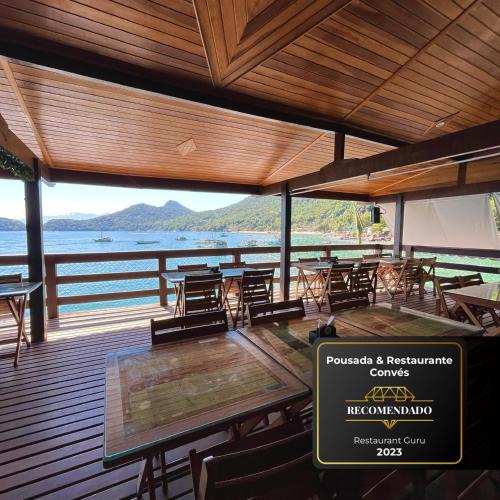 a restaurant with tables and chairs and a view of the water at Pousada Convés - Ilha Grande in Praia de Araçatiba