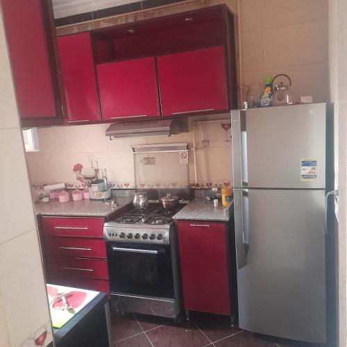 a kitchen with red cabinets and a white refrigerator at الشيخ زايد .روضه زايد in Kafr Abū ʼumaydah