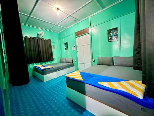 two beds in a room with green walls at Khafii Village in Kampong Pasir Panjang