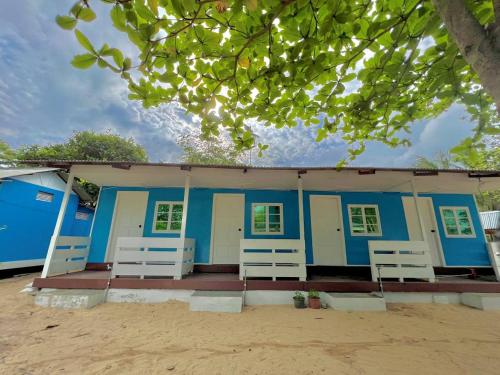 a blue building with white chairs in front of it at Khafii Village in Kampong Pasir Panjang
