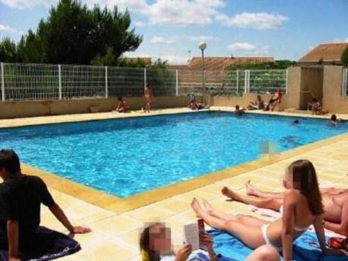un groupe de personnes assises autour d'une piscine dans l'établissement Appartement avec jardin, vue sur étang , proximité mer Gruissan Ayguades, à Gruissan