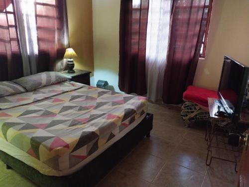 a bedroom with a bed and a tv and windows at Hostal Finca Villa Maria in Filandia