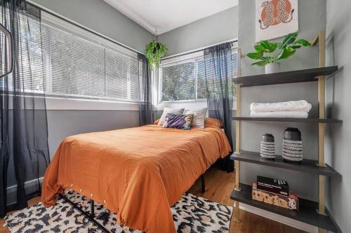 a bedroom with a bed with an orange bedspread and a window at Jungle Themed Apt. Close to Coffee, Food + Shops! in Tampa