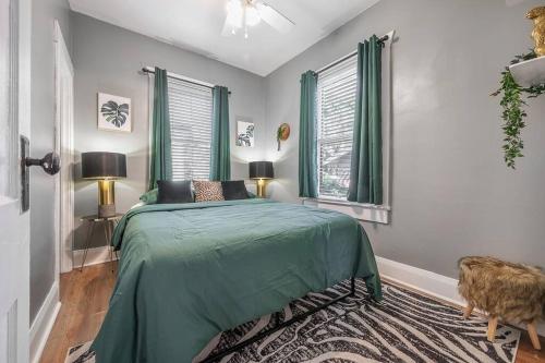a bedroom with a green bed and two windows at Jungle Themed Apt. Close to Coffee, Food + Shops! in Tampa