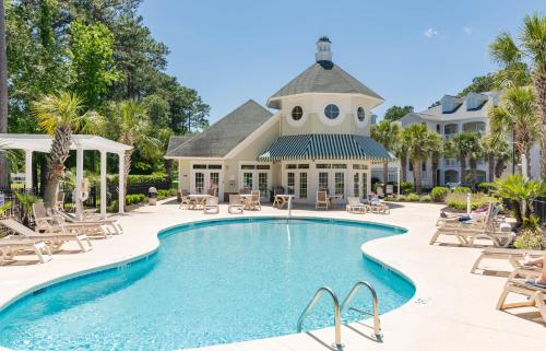 a swimming pool in front of a house with a resort at The Salty Fairway, Golf Course Condo with Resort Style Pool, 5 Miles from Beach, Fully updated in Myrtle Beach