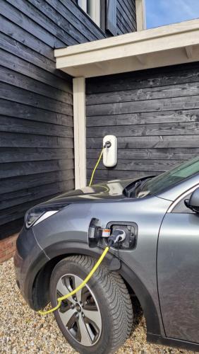 a car parked next to a garage with a yellow cord plugged at B&B De Droomhoeve in Nunspeet