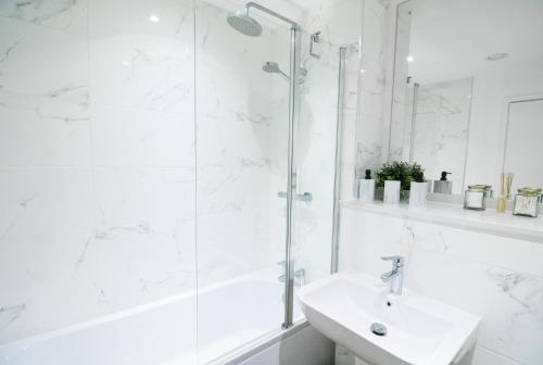 a white bathroom with a shower and a sink at Beautiful place - 2 Bedroom Apartment on Broad Street in Birmingham