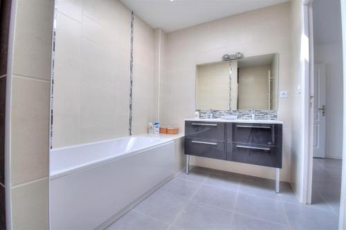 une salle de bain blanche avec une baignoire et un lavabo dans l'établissement Maison de plain-pied 