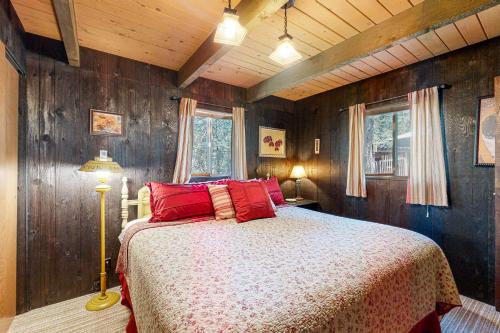 a bedroom with a bed with red pillows and wooden walls at Pine Cone Cabin in Cascade