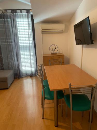 a dining room with a table and chairs and a television at Apartment Enna in Kaštela