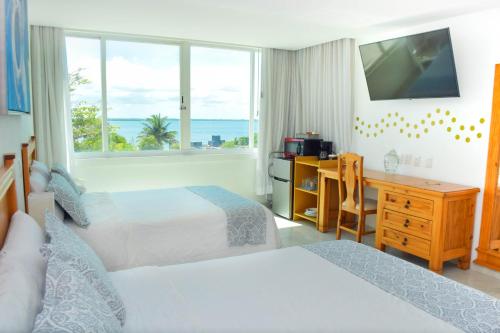 a hotel room with two beds and a desk and a window at Estudio 1A sobre hermosa playa, excelente opción in Cancún