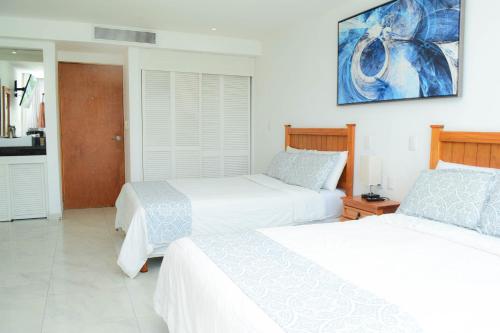 a bedroom with two beds and a painting on the wall at Estudio 1A sobre hermosa playa, excelente opción in Cancún