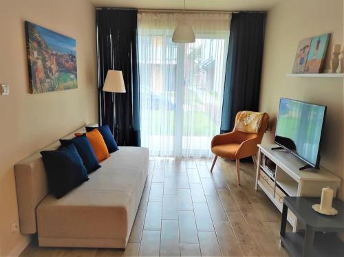 ein Wohnzimmer mit einem Sofa und einem TV in der Unterkunft Apartament na Mierzei Wiślanej nad morzem in Jantar