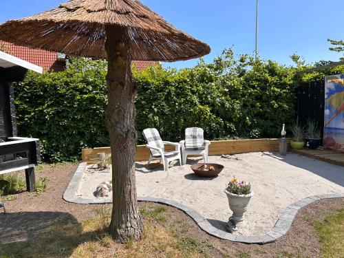 a patio with a umbrella and a chair and a dog at Piccobello Bed & Breakfast Valløby Køge in Valløby