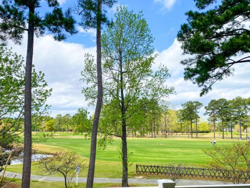 a view of a golf course through the trees at The Salty Fairway, Golf Course Condo with Resort Style Pool, 5 Miles from Beach, Fully updated in Myrtle Beach